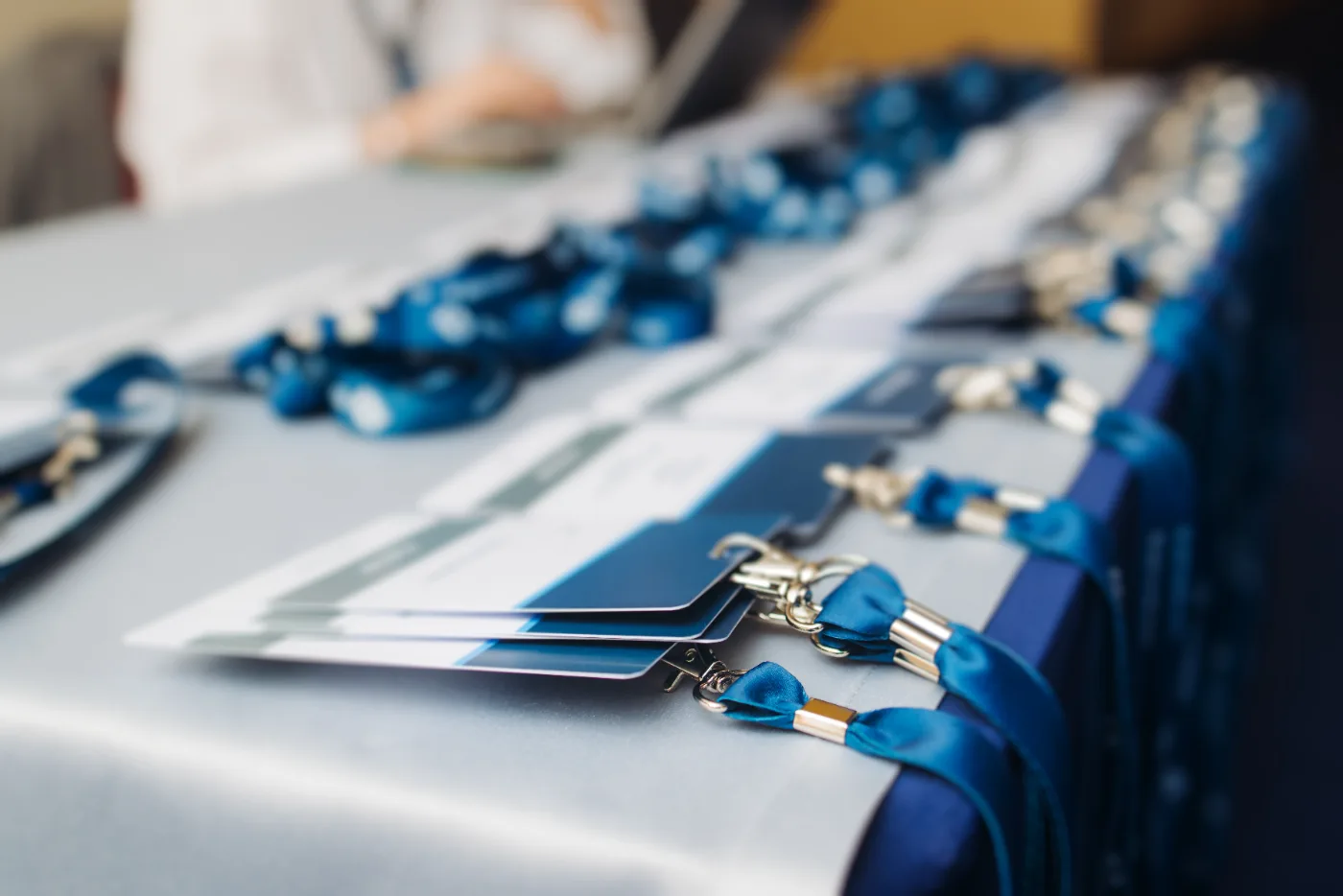 Conference badges on blue lanyards laid out in rows on a registration desk